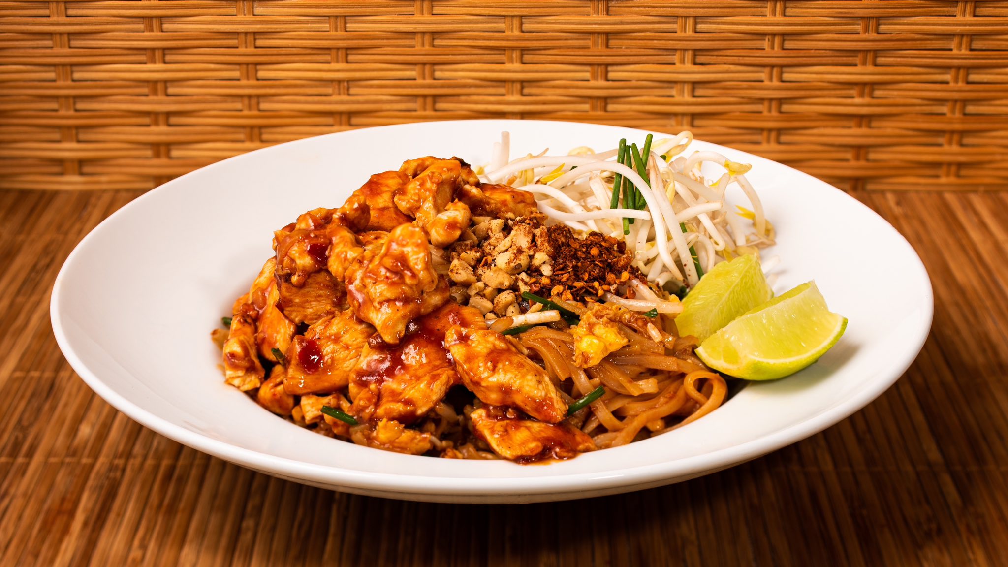 Pad thaï au poulet servi par Nock Thai à Limoux, garni de citron vert, cacahuètes et germes de soja,